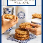Vertical photo of a batch of Crispy Chewy Carolina Coconut Cookies with hands taking two of the cookies and a text title at the top of the photo.
