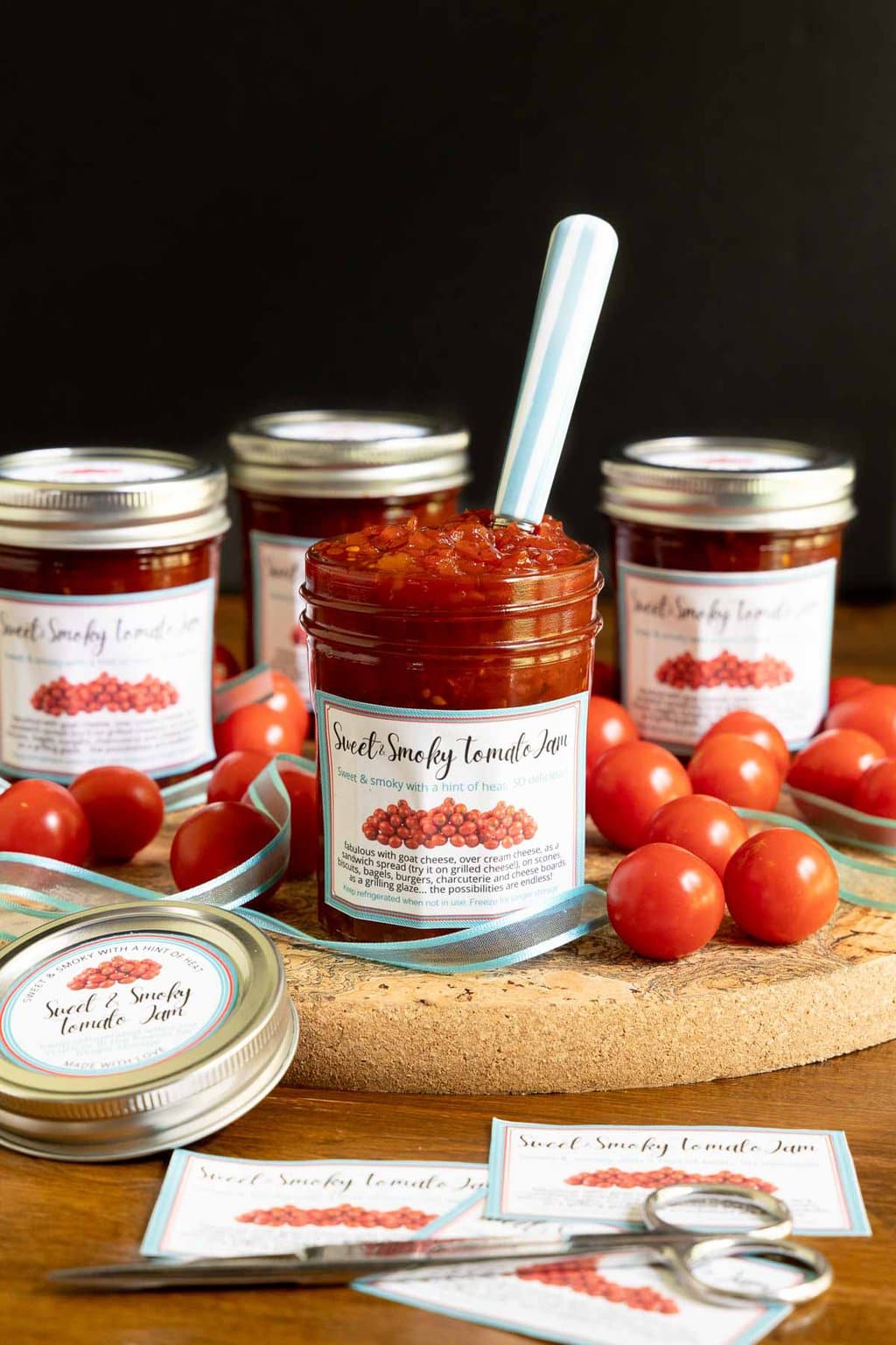 Vertical photo of Sweet and Smoky Tomato Jam in glass jars with labels for gift giving.