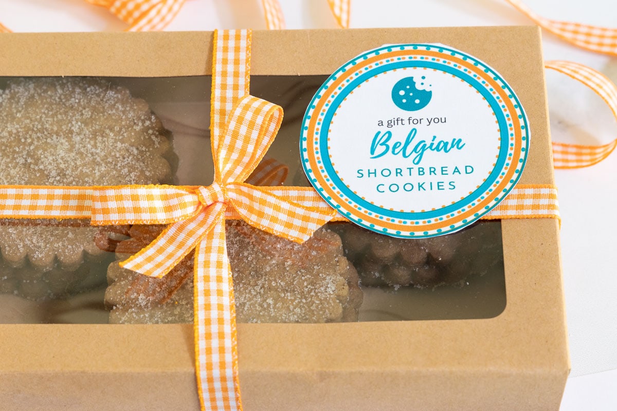 Horizontal photo of Belgian Shortbread Cookies in a window gift box with ribbon and a custom label for gift giving.