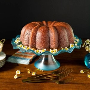 Horizontal photo of a Ridiculously Easy Apple Cider Bundt Cake on a turquoise glass pedestal cake stand.