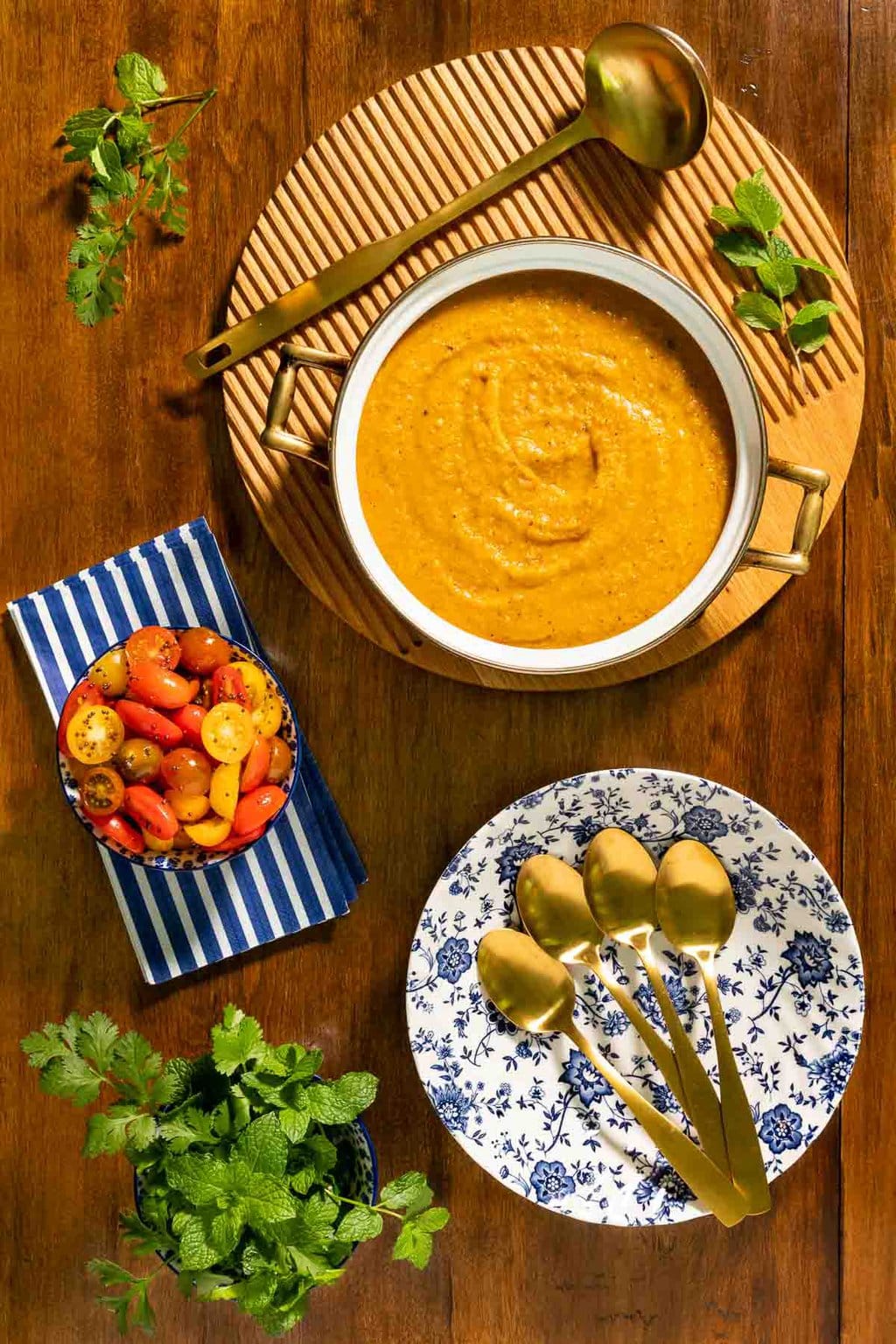 Vertical overhead photo of a pot of Butternut Red Lentil Dal with Gingered Tomatoes on a wood table.