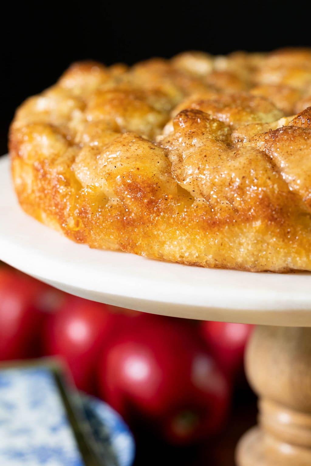 Vertical extreme closeup photo of a Ridiculously Easy Apple Cinnamon Breakfast Focaccia on a pedestal display plate.