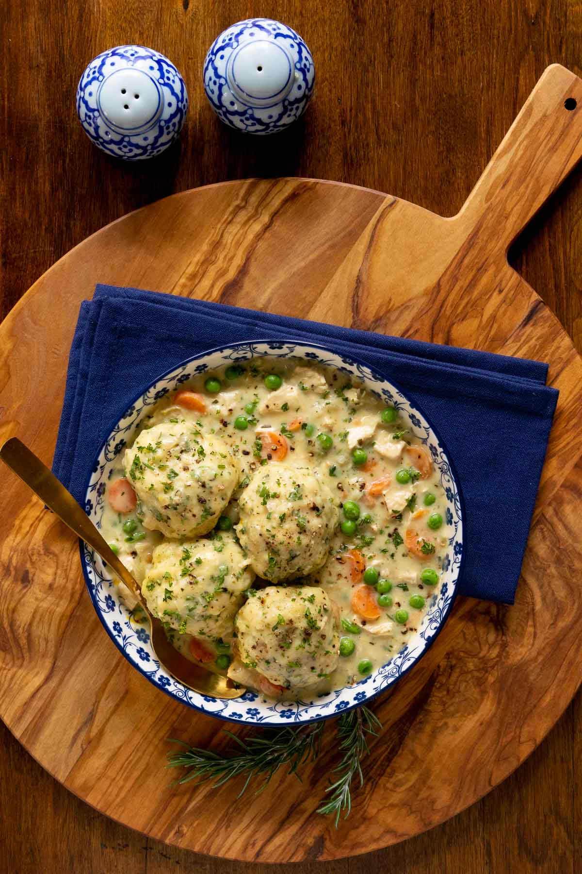 Overhead vertical photo of a serving bowl of Easy Chicken and Dumplings on a wood serving platter.