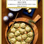 Vertical overhead photo of a cast iron pot of Easy Chicken And Dumplings on a round wood serving board.