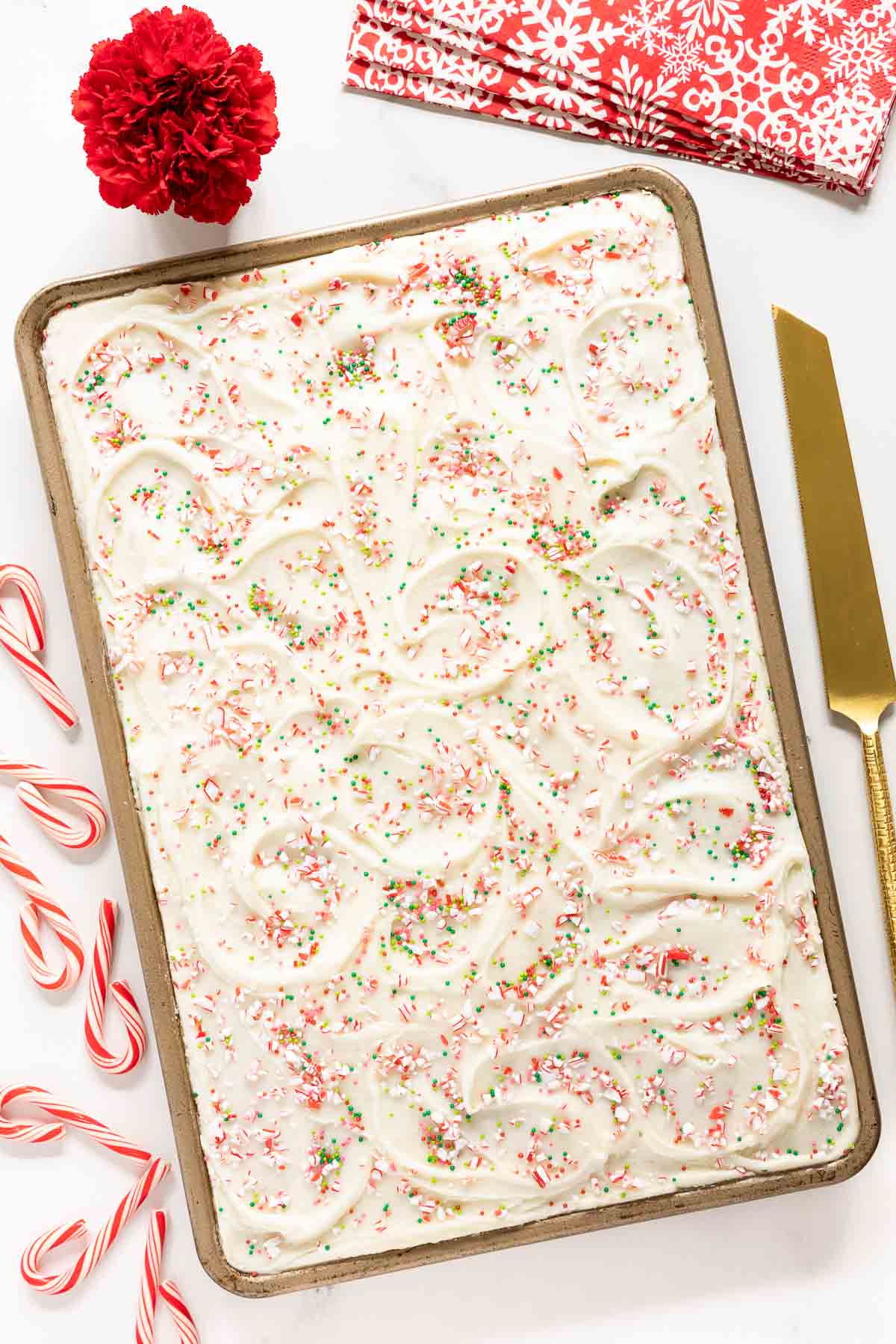 Vertical overhead photo of a Ridiculously Easy Candy Cane Sheet Cake on a gold baking pan surrounded by candy canes.