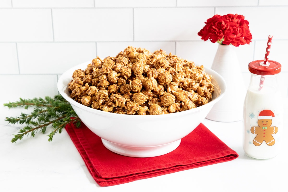 Horizontal photo of a large bowl of Ridiculously Easy Gingerbread Caramel Corn on a festive red napkin.