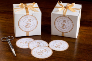 two white boxes filled with almond toffee white chip cookies, tied with a tan satin ribbon with custom labels