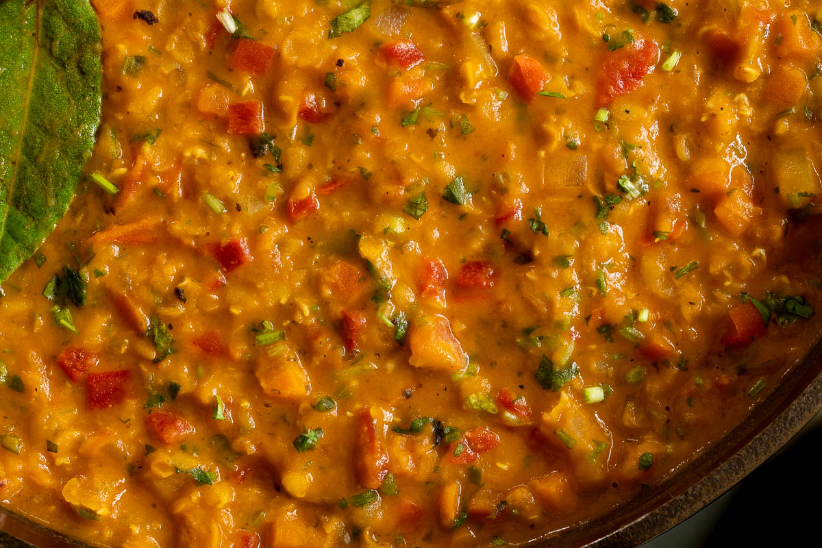 Horizontal overhead extreme closeup photo of a pot of Curried Red Lentil Coconut Soup.