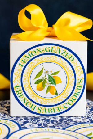 a white box with a yellow ribbon and custom label showing lemon glazed french sable cookies