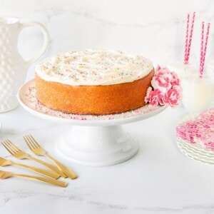 Horizontal photo of a Strawberry-Glazed Pink Velvet Cake with Almond Buttercream on a white pedestal cake stand.