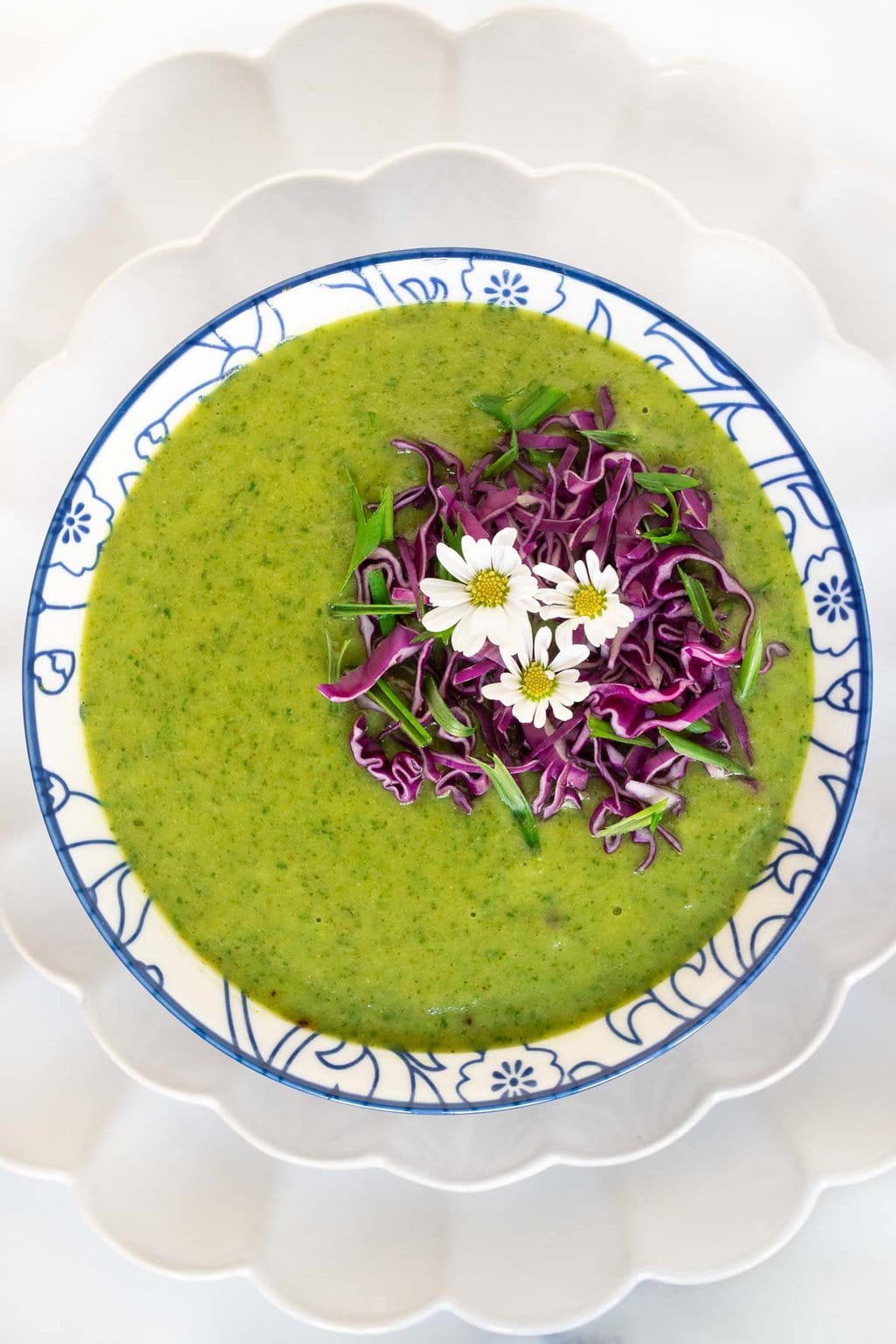 Vertical overhead photo of a bowl of Thai Broccoli Spinach Soup in a blue and white patterned soup bowl.