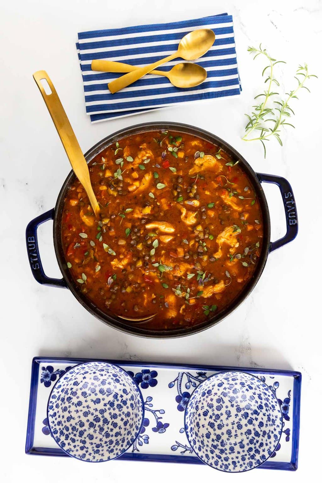 Vertical overhead photo of a cast iron pot of French Lentil Soup on a granite surface.