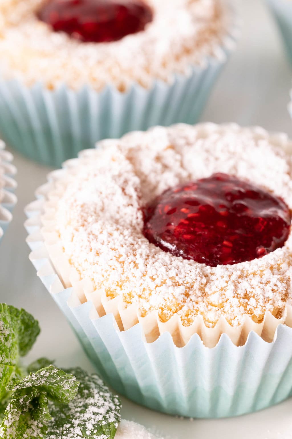 Vertical extreme closeup photo of Ridiculously Easy Scandinavian Raspberry Jam Tarts dusted with powdered sugar.