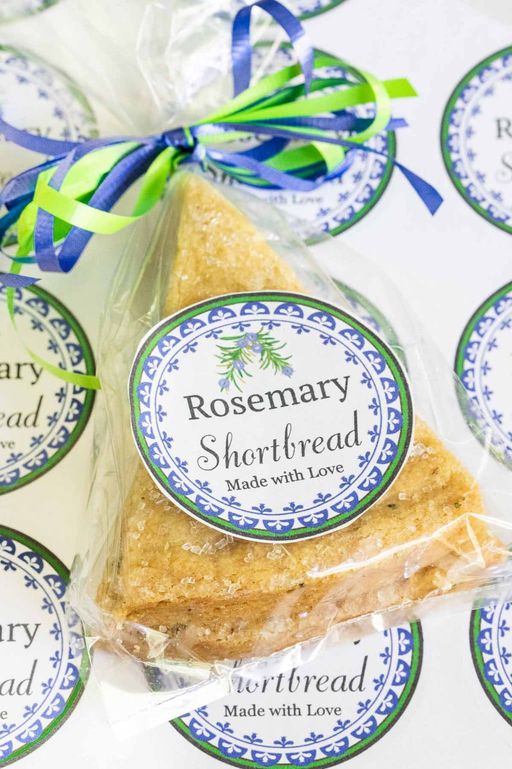 Vertical overhead photo of a slice of Ridiculously Easy Rosemary Shortbread in a plastic bag with custom labels for gift giving.