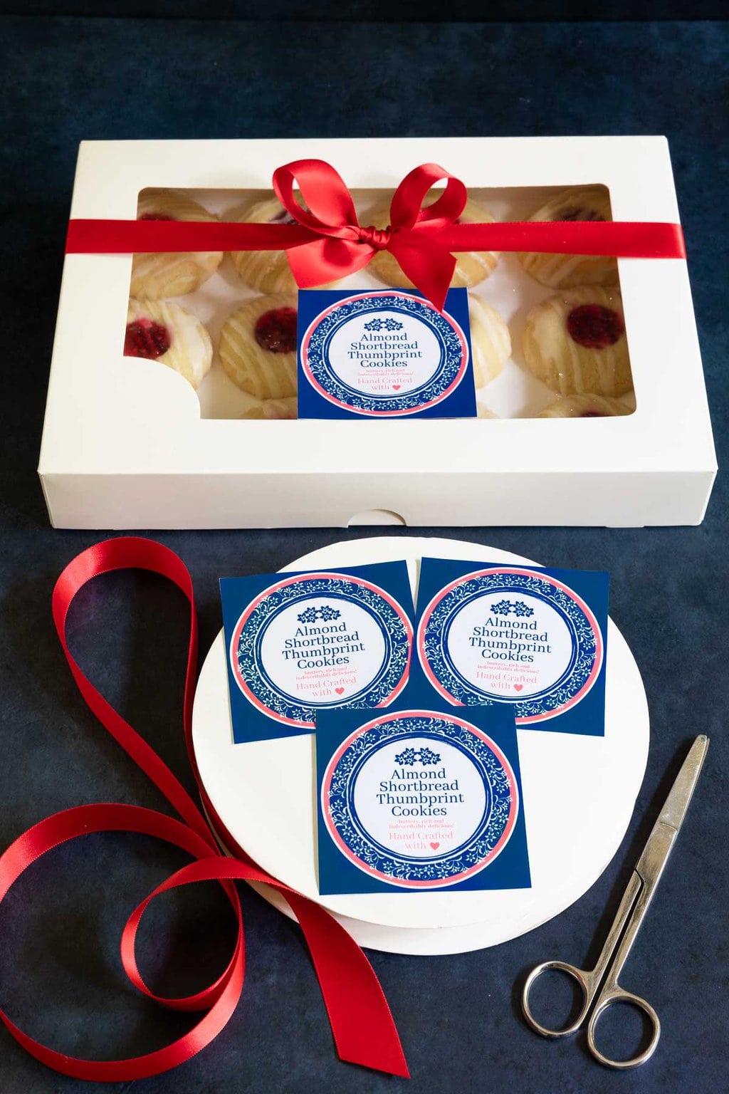 Vertical photo of Almond Shortbread Thumbprints cookies with custom labels for gift giving.