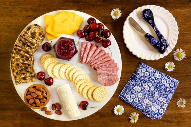 Horizontal overhead photo of a jar of Balsamic Sweet Cherry Preserves in the middle of a charcuterie board.