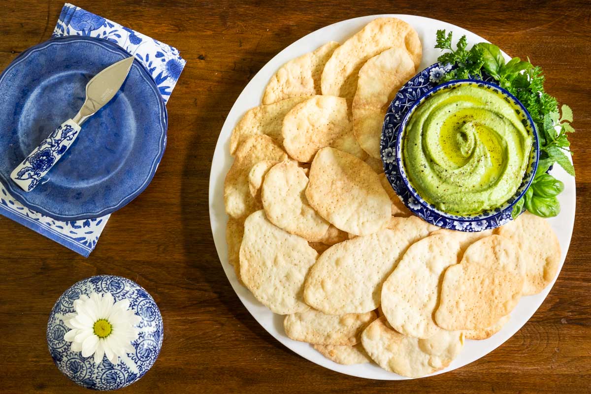 Horizontal overhead photo of a batch of Old Edward's Inn Buttermilk Crackers along with a side of Green Goddess Humus dip.