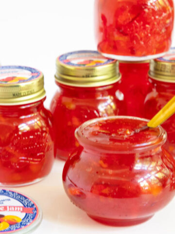 Horizontal photo of a batch of Fresh Nectarine Jam in canning jars with custom labels for gift giving.