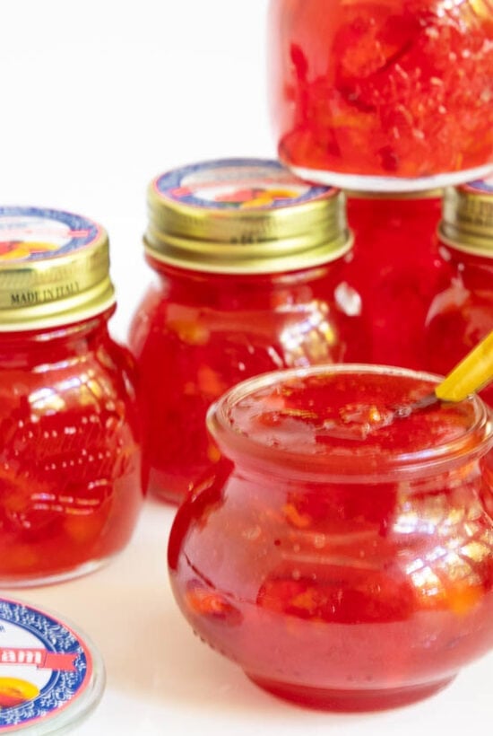 Horizontal photo of a batch of Fresh Nectarine Jam in canning jars with custom labels for gift giving.