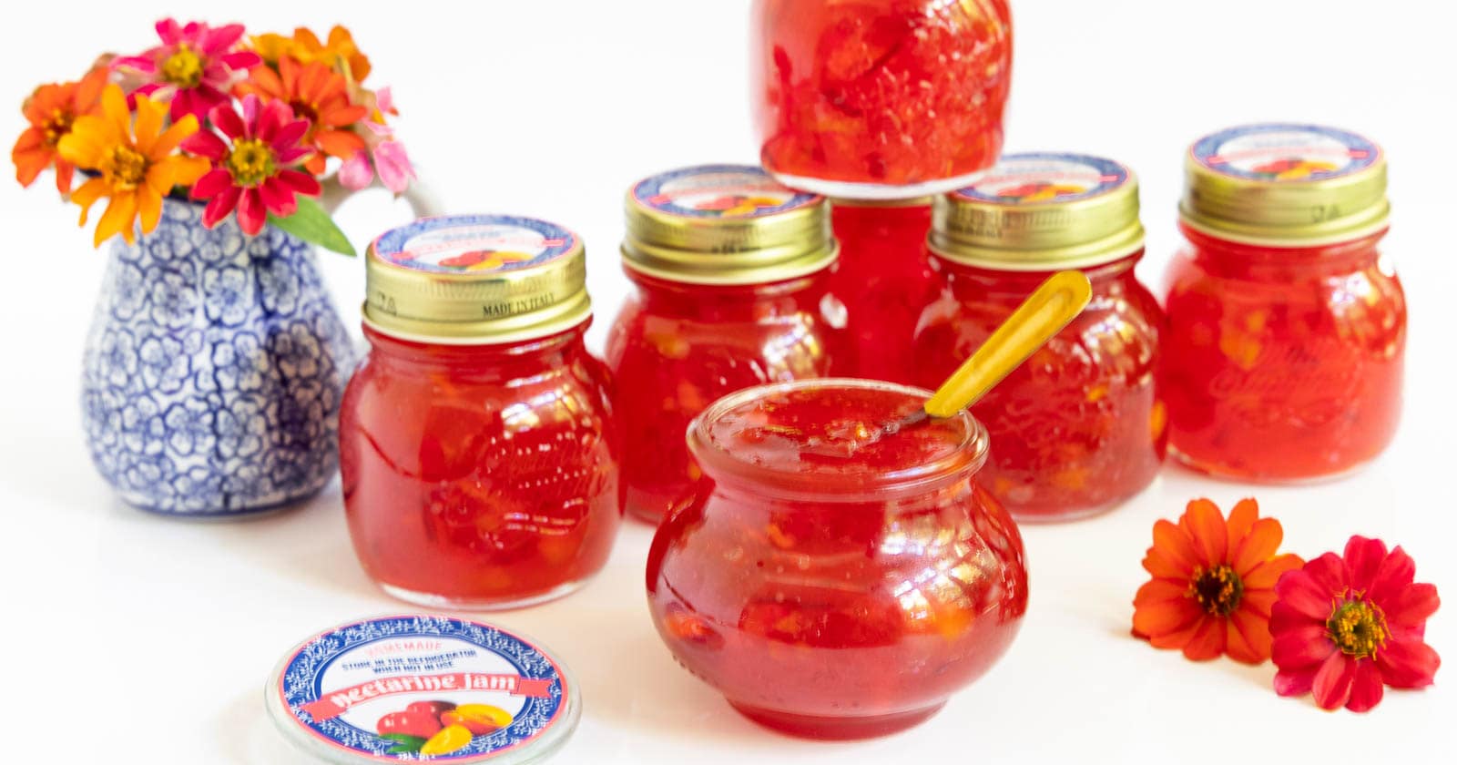 Horizontal photo of a batch of Fresh Nectarine Jam in glass jars with custom labels for gift giving.