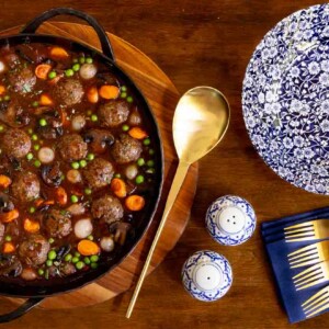 Overhead horizontal photo of a black cast iron skillet of Beef Bourguinon Meatballs (Boulettes de Bœuf Bourguignon).