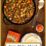 Vertical overhead photo of a cast iron skillet of Easy, Make-Ahead Coq au Vin on a wood table with a side of mashed potatoes.