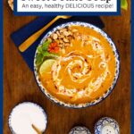 Vertical overhead photo of a bowl of Roasted Sweet Potato Soup garnished with sour cream, peanuts, basil leaves and lime wedges.