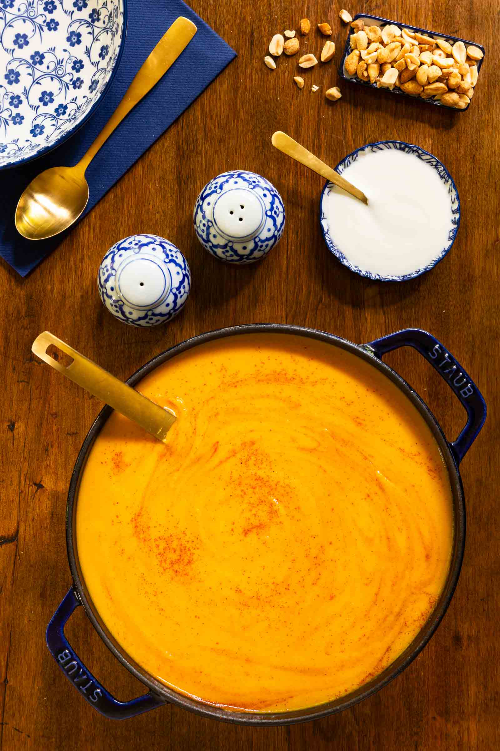 Vertical overhead photo of a cast iron pot of Roasted Sweet Potato Soup on a wood table.