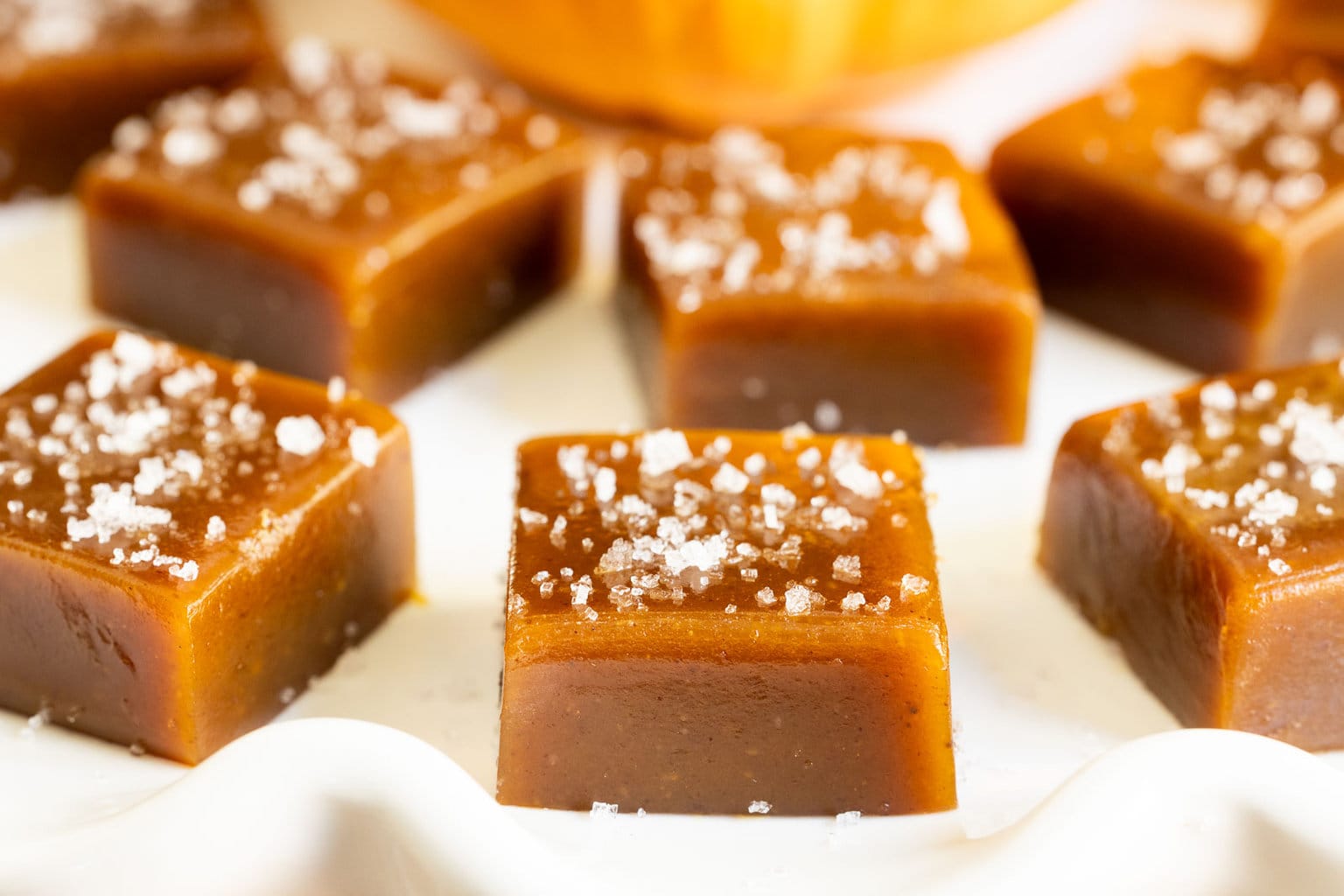 Horizontal extreme closeup photo of a batch of Ridiculously Easy Sea-Salted Pumpkin Microwave Caramels.