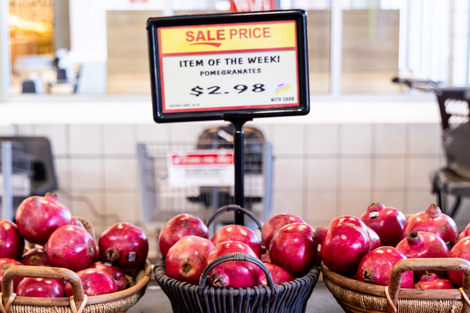 Horizontal photo of a store display of fresh pomegranates in baskets.