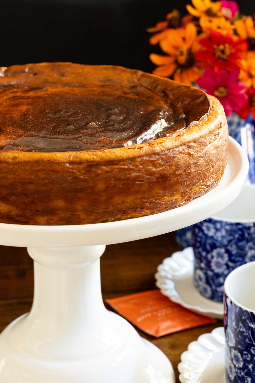 Vertical closeup photo of a Ridiculously Easy Basque Sweet Potato Cheesecake on a white pedestal serving plate.