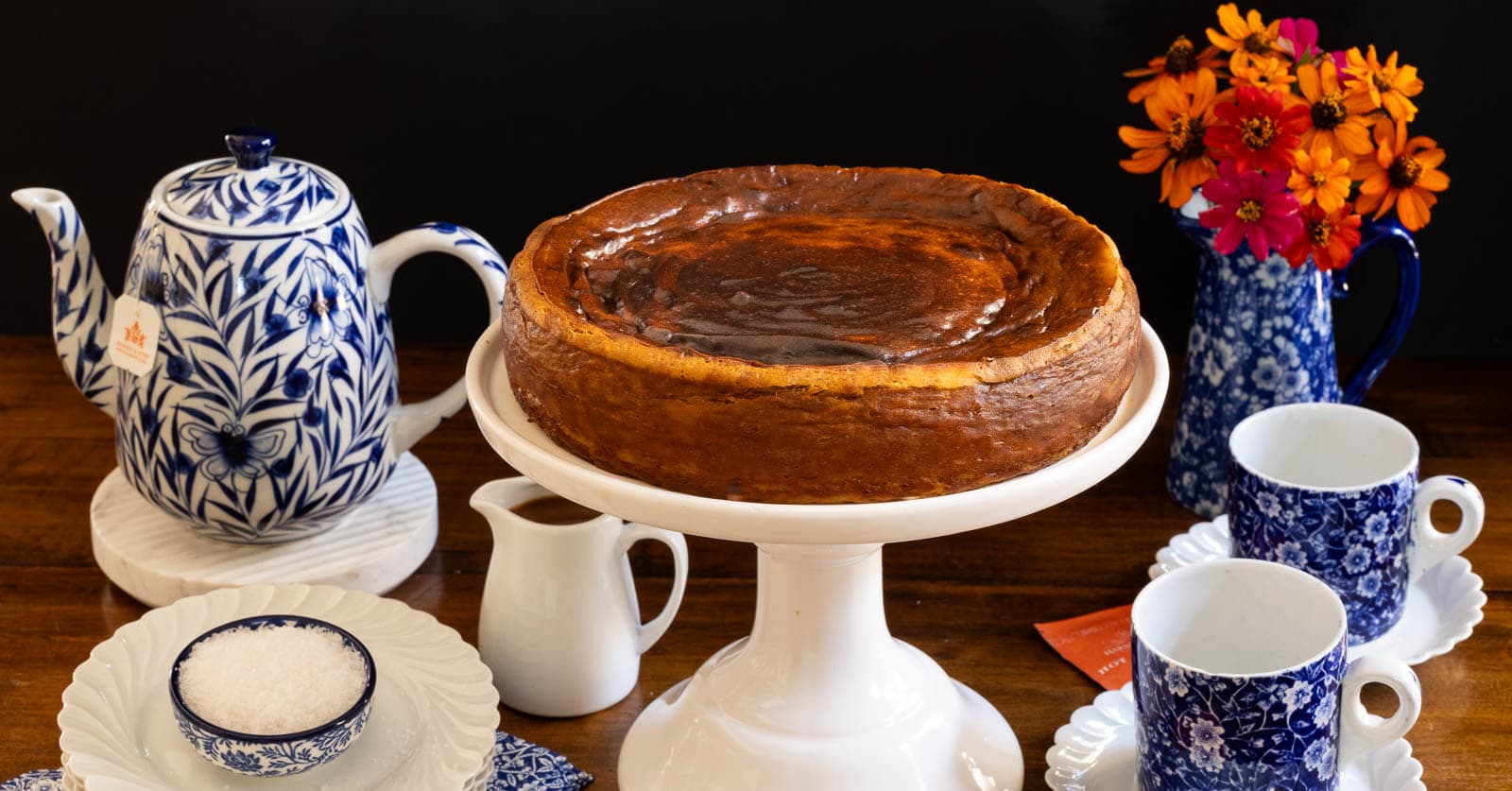 Horizontal photo of a Ridiculously Easy Basque Sweet Potato Cheesecake on a white pedestal serving plate.