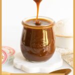 Vertical closeup photo of a Weck jar of Ridiculously Easy Caramel Sauce with a spoon drizzling the caramel back into the jar.