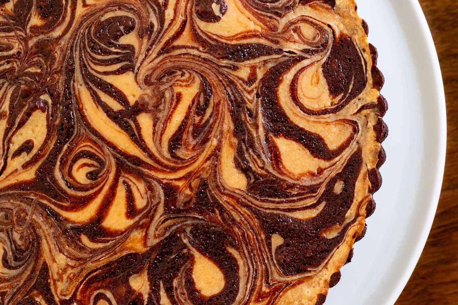 Horizontal overhead closeup photo of a Ridiculously Easy Caramel Cream Cheese Tart on a white serving plate.