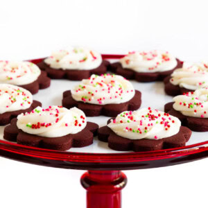 Horizontal photo of a batch of Chocolate Shortbread with Almond Buttercream cookies on a red glass serving plate.