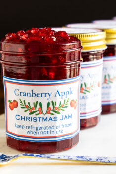 Horizontal closeup photo of a batch of Cranberry Apple Christmas Jam in glass jars.