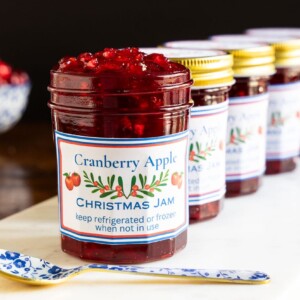 Horizontal closeup photo of a batch of Cranberry Apple Christmas Jam in glass jars.