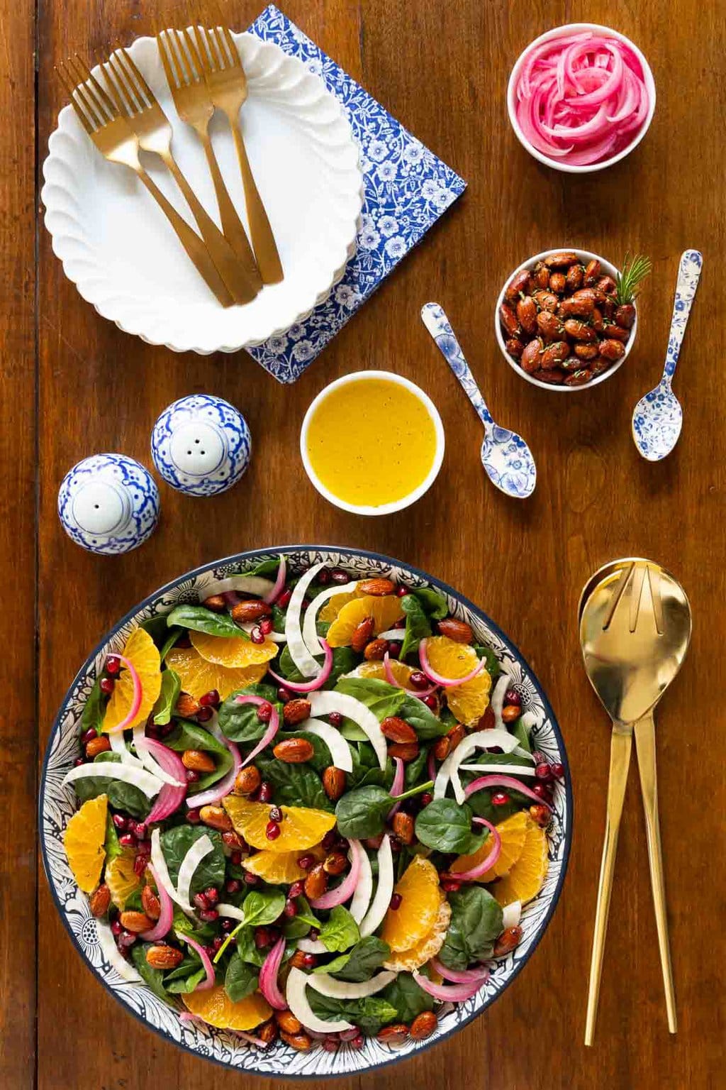 Vertical overhead photo of an Orange Fennel Spinach Salad with Honey White Balsamic Dressing in a blue and white patterned bowl on a wood table.