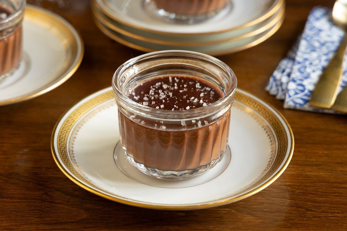 Horizontal closeup photo of a Ridiculously Easy 5 Minute Chocolate Mousse dessert in a glass serving cup on a white and gold plate.