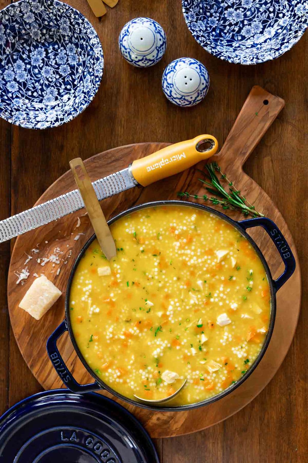 Vertical overhead photo of a pot of Italian Chicken Pastina Soup on a wood cutting board.