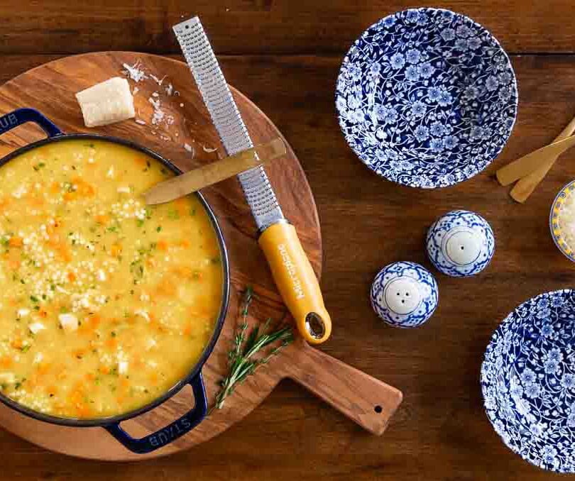 Horizontal overhead photo of a cast iron pot of Italian Chicken Pastina Soup garnished with grated cheese.