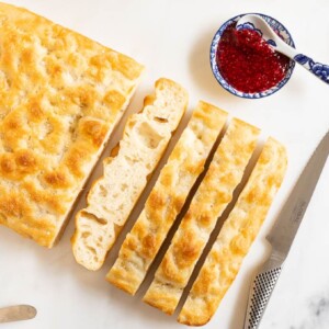Horizontal overhead photo of a loaf of Ridiculously Easy Same Day Focaccia Bread on a white cutting board.