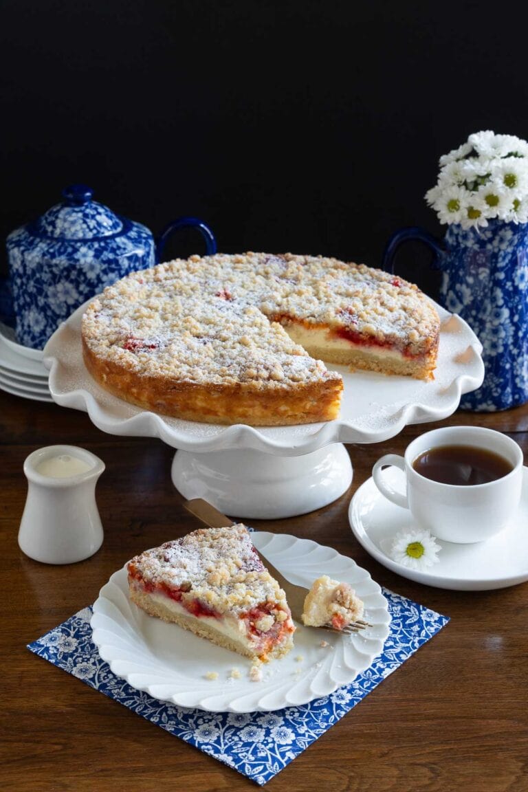 Italian Raspberry Jam Ricotta Cake on a white cake stand with a slice cut