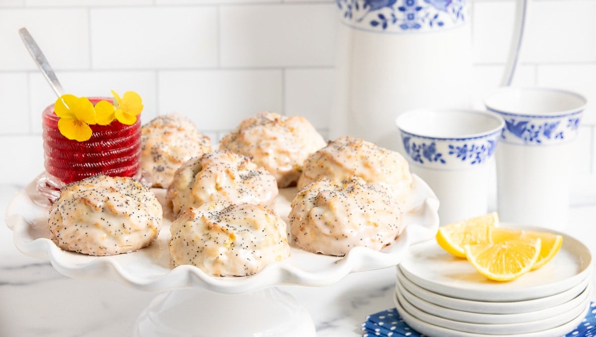 Horizontal photo of a batch of Lemon Poppy Seed Scones on a white pedestal serving plate.