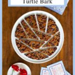 Vertical overhead photo of a batch of Ridiculously Easy Chocolate Caramel Turtle Bark on a white serving plate with custom labels for gift giving.