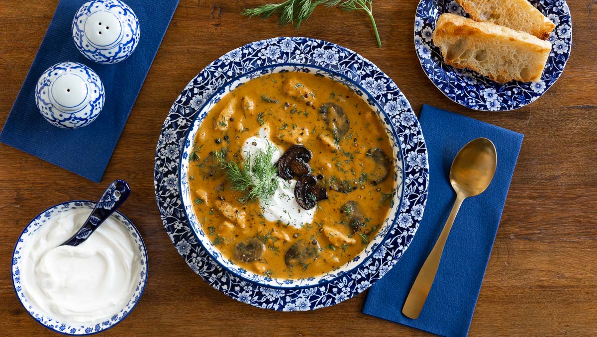 Horizontal overhead photo of a bowl of Low Carb Hungarian Mushroom Soup in a blue and white patterned soup bowl with focaccia bread.