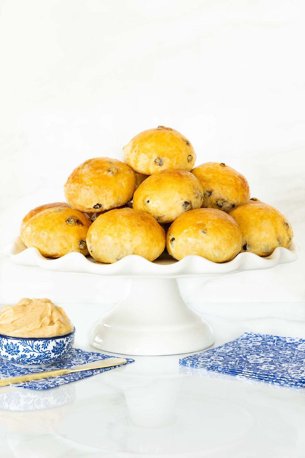 Vertical photo of a stack of Irish Freckle Bread Rolls on a white scalloped serving plate.