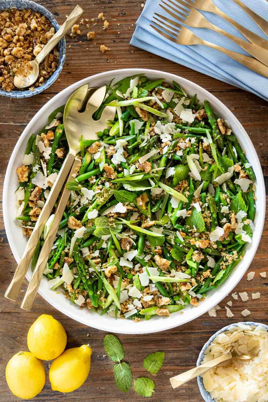 Vertical overhead photo of a Lemony French Green Bean Asparagus Salad garnished with walnut-panko topping and shaved Parmesan cheese.
