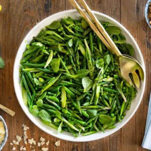 Horizontal overhead photo of a Lemony French Green Bean Asparagus Salad garnished with walnut panko topping and shaved Parmesan cheese.