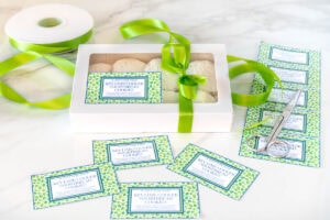 a box of key lime cooler cookies packaged in a white box with a clear lid and tied with a bright green ribbon complete with a custom label.